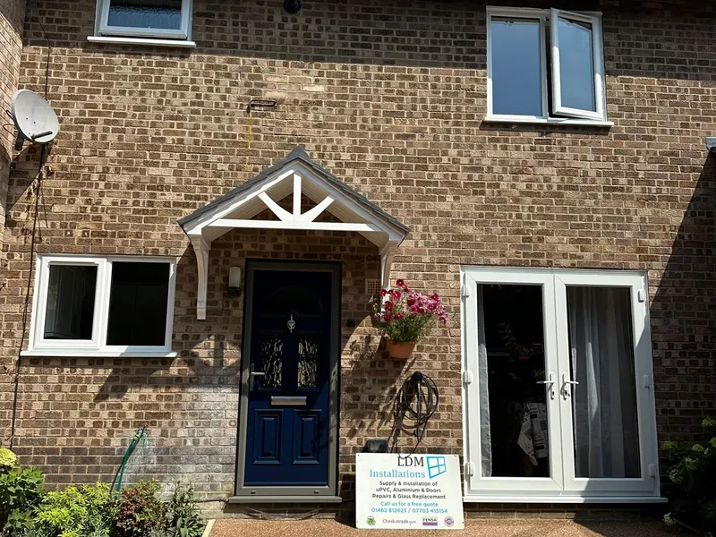 Navy composite front door and white uPVC windows installed on a semi-detached house