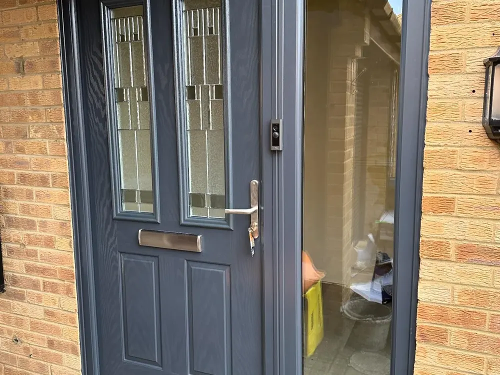Anthracite composite front door with a glazed side panel replacing an old entrance door