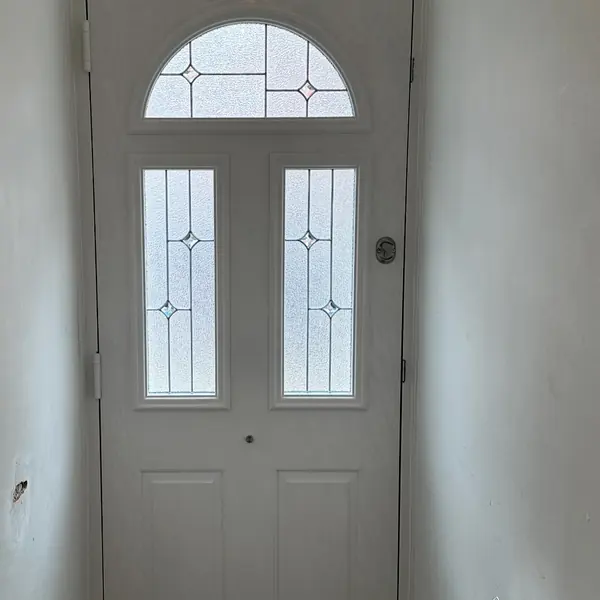 Cream composite door with arched decorative glass viewed from the hallway