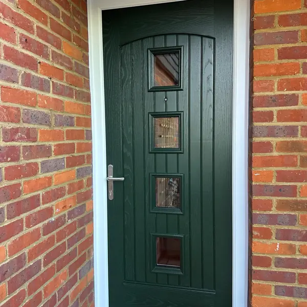 Green composite front door in a brick porch