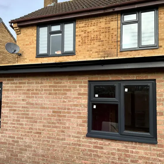 Anthracite grey windows on a two-storey brick house and extension