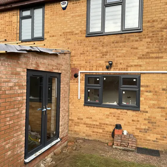 Rear of a yellow brick house with anthracite windows and French doors