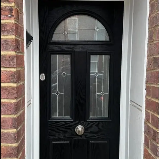 Black composite front door with arched glazing and a glazed top light