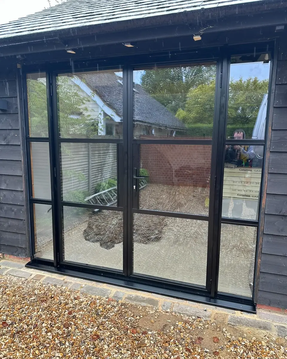Black slim-framed glazed doors with grid bars on a timber garden room