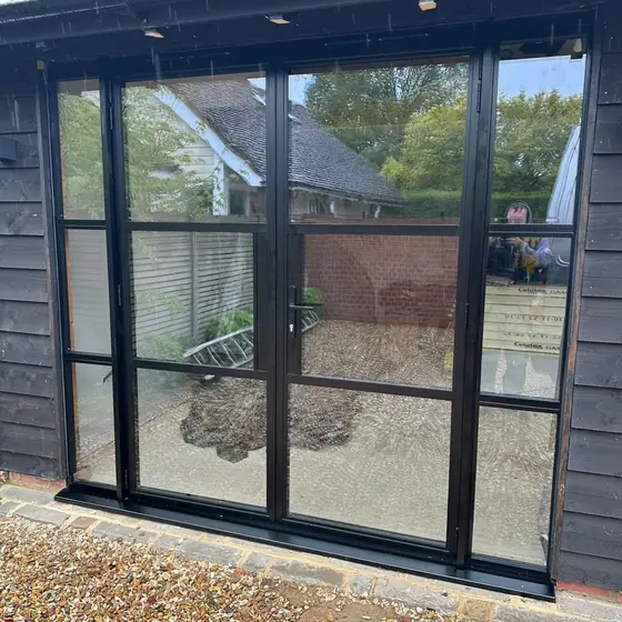 Black slim-framed glazed doors with grid bars on a timber garden room