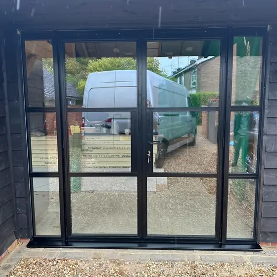 Black slim-framed glazed doors and screen on a timber building