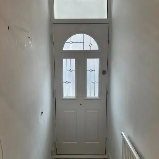 Cream composite front door with arched glass seen from the hallway