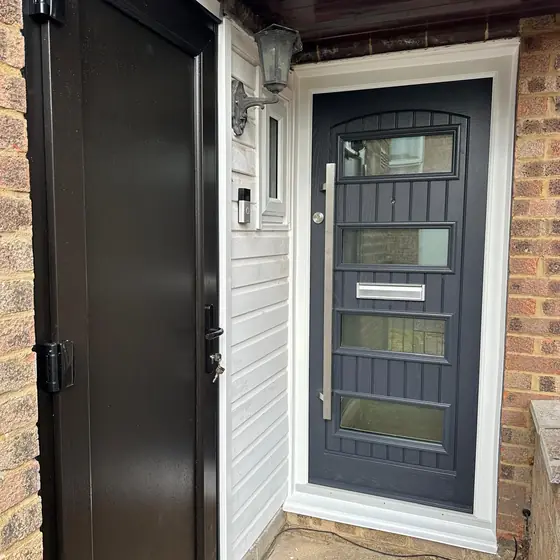 Grey contemporary composite door with glazed strips and a bar handle
