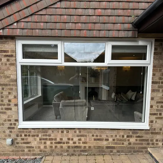 Large white picture window with top openers on a brick extension