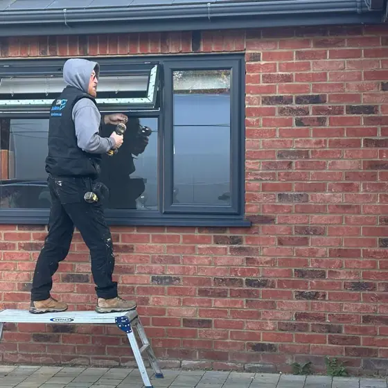 LDM Installations fitter on a step fitting an anthracite grey window