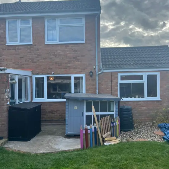 Rear of a brick house with new white windows seen from the garden