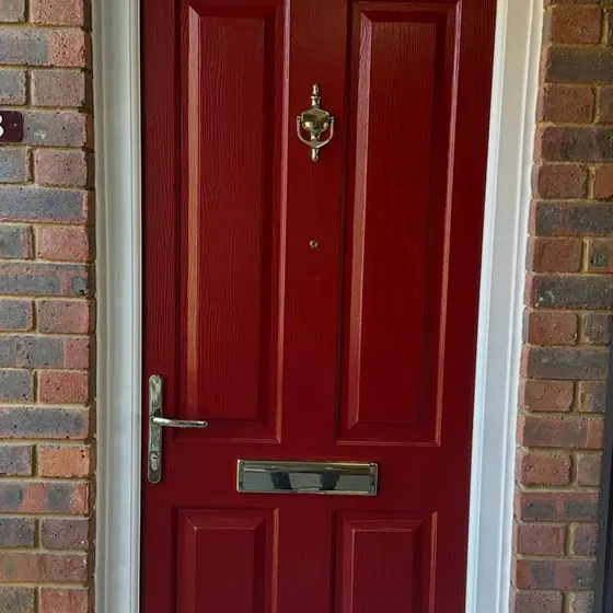 Red panelled composite front door with a gold knocker and letterplate