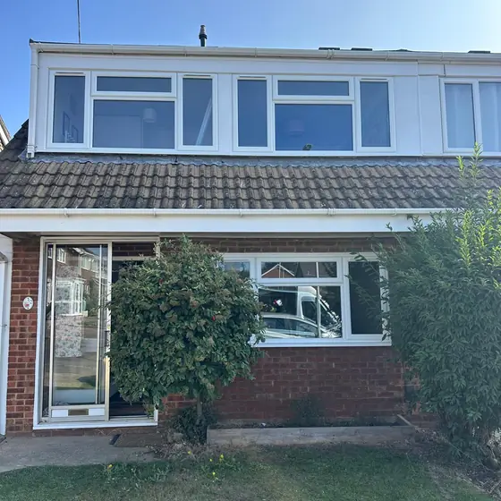 Front of a semi-detached house with new white windows and a porch
