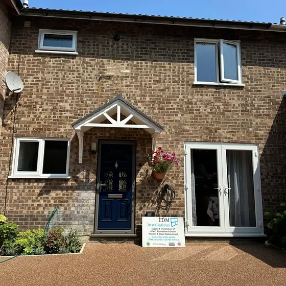 Terraced house with a navy composite front door, white windows and French doors