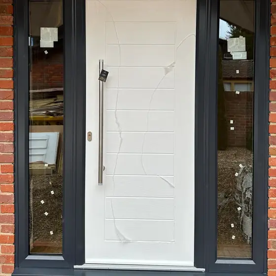 White contemporary front door with long bar handle and anthracite glazed side panels
