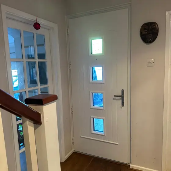 White contemporary front door with square glazed panels seen from inside the hallway