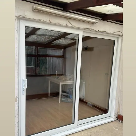 White sliding patio door fitted between a room and a conservatory