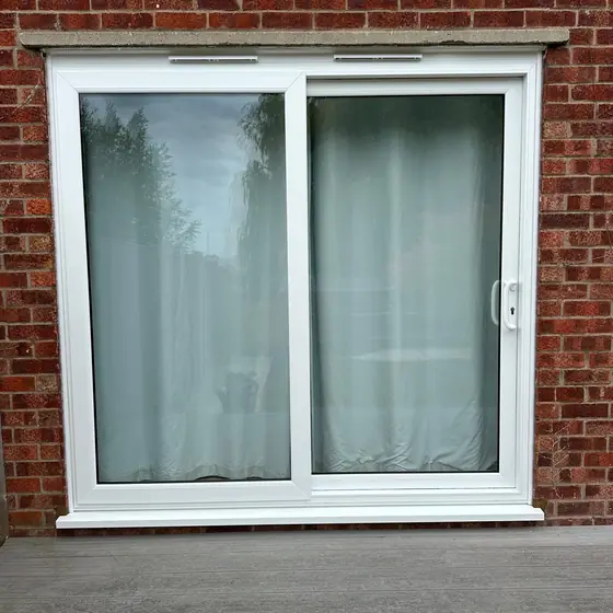 White sliding patio door fitted to the rear of a brick house