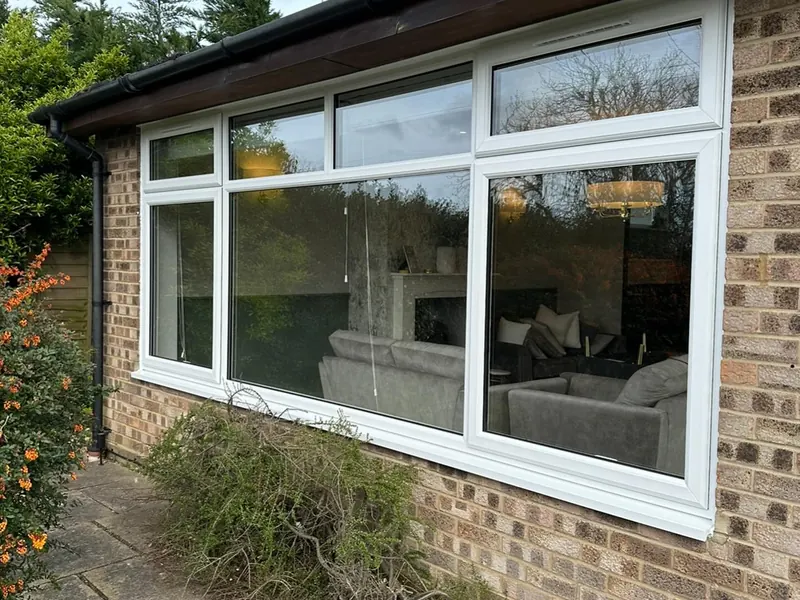 New white uPVC windows on a brick house viewed from the garden